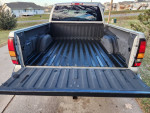 Empty bed of a 2006 GMC Sierra 1500 truck, featuring a black liner and side wheel wells.
