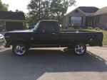 1973 Ford F-100 Short Bed truck, black exterior, new engine, modern upgrades, showcased in residential area.