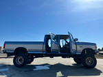 1995 Ford F350 Quad Cab 4WD with monster lift and new tires, showcasing its impressive features.