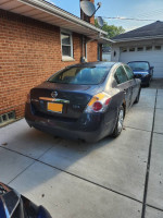 2009 Nissan Altima 2.5S in blue/gray color parked with visible body damage and rust.