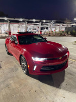 2018 Chevrolet Camaro 1LT Coupe in red with RS package, showcasing its sleek design under evening lights