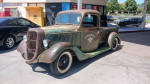 1936 Ford pickup truck 'La Cucaracha' with unique patina and modifications parked at a gas station