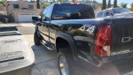 2003 Chevrolet Silverado 1500, black extended cab truck with 4x4 and chrome wheels parked in driveway.