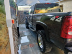 2003 Chevrolet Silverado 1500 in a driveway, showcasing its 4x4 capabilities and chrome alloy wheels.