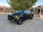 2019 Ford Raptor in black, parked on the street, showcasing panoramic roof and carbon fiber package.