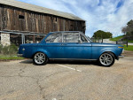 1968 BMW 1600 2002 in blue color parked on a street with rustic buildings in the background