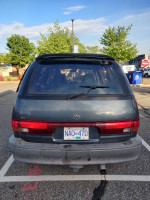 Rear view of a 1993 Toyota Previa LE minivan parked with a scenic backdrop, showcasing its unique design.