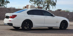 2013 BMW 740i RWD side view showcasing sleek design and premium features with black wheels.