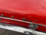Close-up of a red 1968 Ford Mustang trunk showing minor rust and chrome detailing