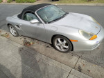 Silver 1998 Porsche Boxster parked with convertible top, showcasing its sleek design and sporty appeal.
