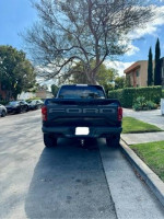 Rear view of a black 2020 Ford F-150 Raptor parked on the street, showcasing its distinctive design.