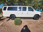 Side view of a 2012 Ford E-350 XLT 15 passenger van, white color, parked in a clean outdoor area.