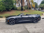 2017 Chevrolet Camaro 2LT convertible with black rims parked on a street, showcasing its sleek design.