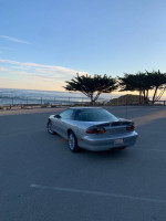 2002 Chevrolet Camaro SS parked by the ocean, showcasing its sleek design and sunset backdrop.