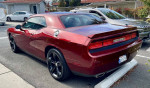 2014 Dodge Challenger SXT 100th Anniversary Edition parked, showcasing its sleek design and red exterior.