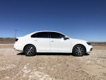 2018 Volkswagen Jetta SE in white, side view on a gravel road, showing sleek design and alloy wheels.