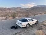 1987 Chevrolet Corvette parked on a desert road, showcasing its sleek design and scenic backdrop.