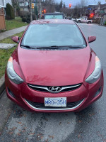 Front view of a 2012 Hyundai Elantra in good condition, showing clean lines and a shiny red finish.