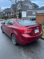 Red 2012 Hyundai Elantra parked in good condition with winter tires, showcasing clean design and no major damage.