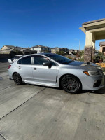2016 Subaru WRX STI in silver parked, showcasing its sporty design and aftermarket features.