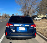 Rear view of a 2011 Subaru Outback, a blue all-wheel drive car parked on the street.