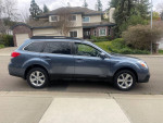 Side view of a well-maintained 2013 Subaru Outback 2.5i AWD parked in a residential area.