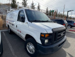 2013 Ford E-350 cargo van parked, used for plumbing and heating services, showcasing wear but functional condition.