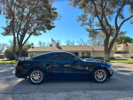 2012 Ford Mustang V6 in black, parked outdoors with a clear blue sky and trees