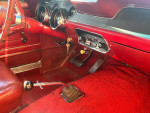 Interior view of a candy apple red 1967 Ford Mustang with red upholstery and a 4-speed manual transmission.
