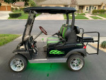 Custom Club Car Precedent golf cart with a sporty design and unique green flame decals, parked on a driveway.