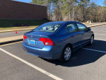 2006 Honda Civic blue sedan parked with clear view of rear and side, featuring minor scratches and a clean interior.