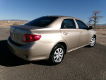 2009 Toyota Corolla LE in gold color parked on a road, showcasing its sleek design and low mileage features.