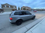 2009 BMW X3 SUV parked on the street, featuring a silver exterior and blacked-out wheels.