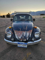 Front view of a 1970 VW Beetle with rustic paint, showcasing its unique character and new seats from a 2015 Kia Soul.
