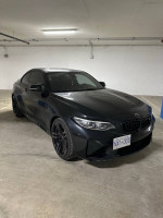 2018 BMW M2 F87 in a parking garage, showcasing its sleek design and modifications.