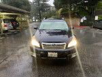 Front view of a 2012 Subaru Outback 2.5L Premium in dark blue, parked in a rain-soaked area.