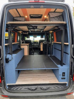 Interior view of a modified 2023 Mercedes-Benz Sprinter van with sleeping and seating space for 4.