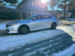 2016 Kia Optima parked on snowy street, showcasing clean exterior and modern design with excellent condition.