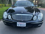 Front view of a 2004 Mercedes E320 luxury sedan, black exterior, showcasing headlights and grille.