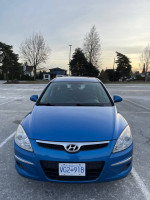 Front view of a blue 2011 Hyundai Elantra GLS FWD parked in an open area, showcasing its sleek design.