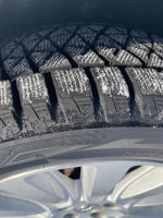 Close-up of Bridgestone Blizzak snow tire tread on a 2015 Toyota Sienna LE, showing excellent grip for winter driving.