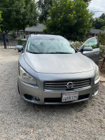 2009 Nissan Maxima in good condition with leather interior and sunroof parked in a gravel driveway.