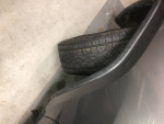 Close-up of a tire leaning against a dark SUV in a garage.