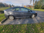 Side view of a clean 2013 Toyota Prius Plug-In Hybrid parked on a driveway, showcasing its eco-friendly design.