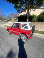 1989 Suzuki Sidekick JLX 4x4 parked on the street, showing its red exterior and white convertible top.