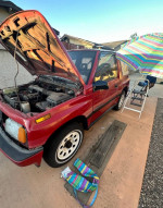 1989 Suzuki Sidekick JLX in red with hood open, needing repairs and new paint.