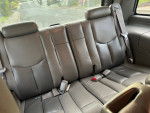 Interior view of the back seats in a 2006 GMC Yukon Denali, showcasing leather upholstery and seatbelts.