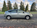 2009 Toyota Prius in silver parked on the street with trees in the background, showcasing its clean exterior.