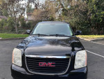 Front view of a well-maintained 2009 GMC Yukon SUV with a black exterior parked in a residential area.