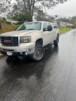 2007 GMC Sierra 2500HD 4x4 diesel truck, fully loaded, parked on a wet street with electric steps and backup camera.
